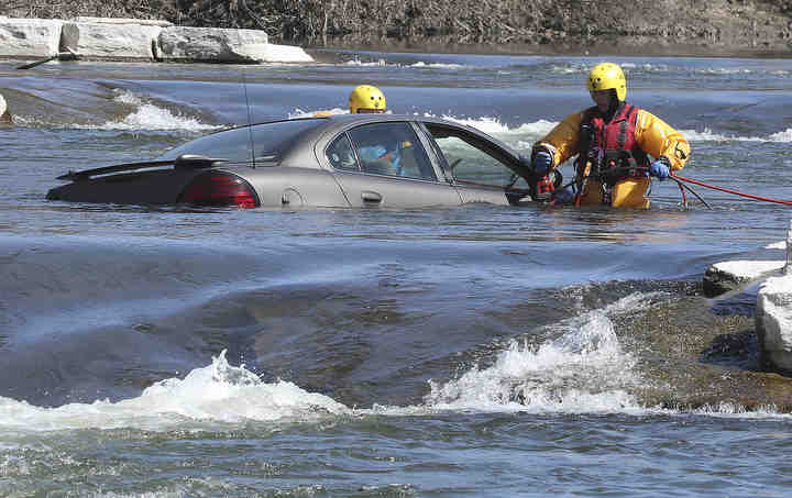 Members of the Springfield Fire Division wade out into rapids at the white water recreation area along Buck Creek to recover a car. The driver of the car was rescued earlier by the fire department after driving into the river.     (Bill Lackey / Springfield News-Sun)
